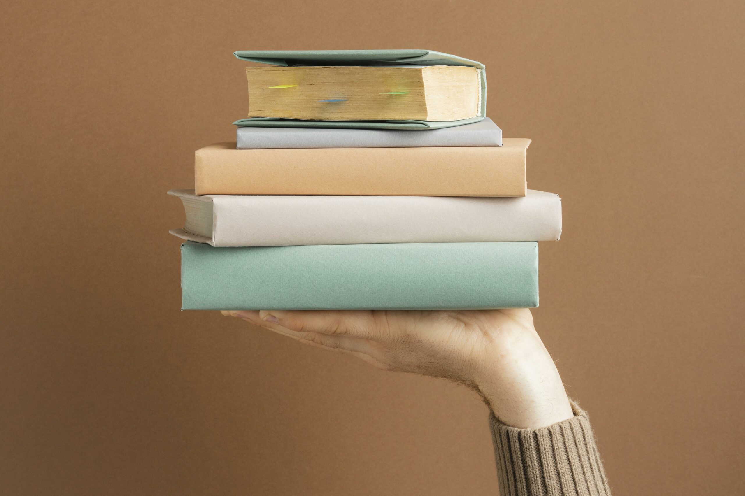 mão masculina segurando varios livros de negócios para empreendedores